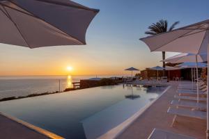 潘泰莱里亚Pantelleria Dream Resort的日落时分带遮阳伞和海洋的游泳池