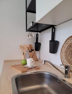 德累斯顿Gemütliches helles Appartement的一个带水槽的厨房台,在切板上放杯