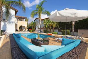 阿依纳帕Villa Regina的一个带蓝色沙发和遮阳伞的游泳池