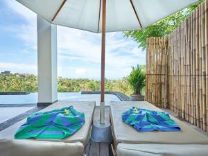 艾湄湾Villa Mimpi Tamarind的天井设有两张床和遮阳伞。