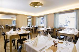 瓦尔斯阿尔皮纳酒店的餐厅设有白色的桌椅和窗户。