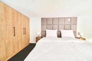 新塔尔格Na Fursie Apartments & Rooms的卧室配有一张白色大床和木制橱柜。