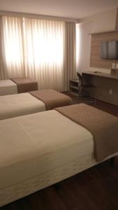 伊达贾伊Hotel 7 Itajaí的酒店客房配有两张床和一张书桌