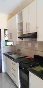 曼齐尼Manzini, Park Vills Apartment, No 103的厨房配有白色橱柜和炉灶烤箱。