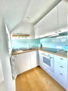 爱丁堡Loft apartment in Joppa的厨房铺有木地板,配有白色橱柜。