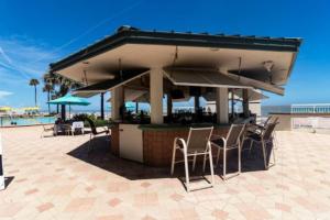 代托纳海滩Coastal Hideaway Oceanview Condo的海滩上的酒吧配有椅子和遮阳伞