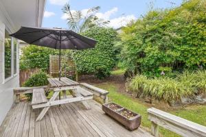 奥克兰Gorgeous 2BR Central Akl Retreat - WI-FI - Netflix的木甲板上配有野餐桌和遮阳伞