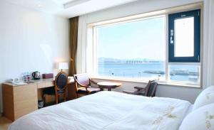 木浦市丰塔纳海滩酒店的配有一张床、一张书桌和一扇窗户的酒店客房