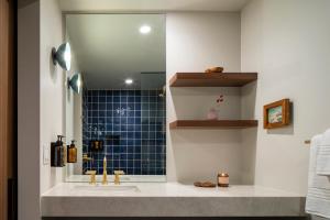 大熊湖Hotel Marina Riviera的浴室设有水槽和蓝色瓷砖淋浴。