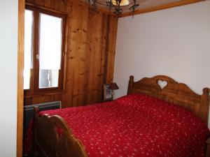 欧苏瓦Chalet Aussois, 6 pièces, 14 personnes - FR-1-508-28的一间卧室配有一张带红色床罩的木床