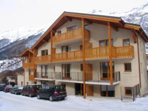 兰斯勒维拉德Appartement Lanslevillard, 2 pièces, 6 personnes - FR-1-508-107的一座大型公寓楼,里面的汽车停放在雪中