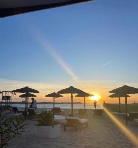萨尔雷波尔杜索尔公寓酒店的海滩上摆放着椅子和遮阳伞,日落