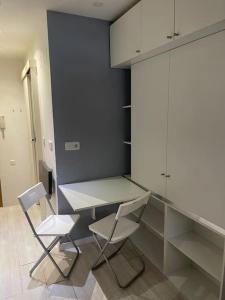 马德里Lovely Loft Bernabéu Madrid的厨房配有两把椅子、一张桌子和橱柜。
