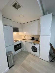 马德里包萨19号公寓的厨房配有白色橱柜和洗衣机。