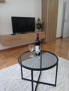 尼什Welcome Apartments的玻璃桌,带一瓶葡萄酒和两杯