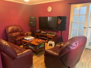 珀斯Lovely house in canning vale的客厅配有2把皮椅和平面电视