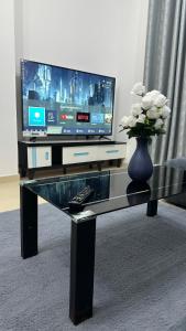 阿吉曼2 bedrooms new brand with amazing view的一张带电视的玻璃桌和一个花瓶