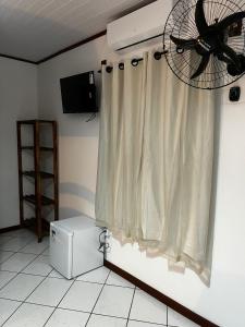 阿拉夏奇巴海滩Luar de Araçatiba Suítes的客房设有吊扇和窗帘
