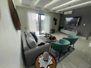 圣地亚哥洛斯卡巴Soha Panorama B13 King Bed High Floor Balcony View的客厅配有沙发、椅子和电视