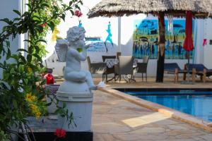 南威Daniel Zanzibar Hotel的美人鱼雕像坐在游泳池旁的柱子上