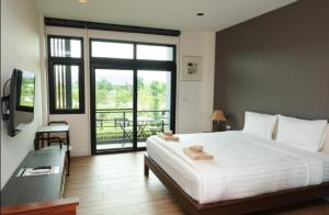 坤西育府Ravin Home ราวินโฮม的一间带一张白色大床的卧室和一个阳台