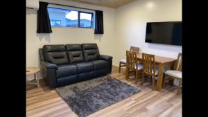 HopeCountry Retreats On Ranzau 4的客厅配有黑色真皮沙发和桌子