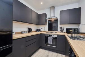 利兹Homebird Property - Salisbury House的厨房配有黑色橱柜和炉灶烤箱。