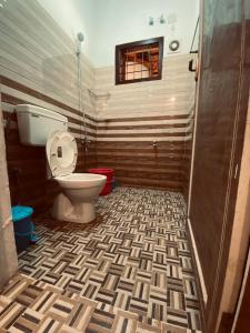 瓦亚纳德3 Hills Hostel的一间带卫生间的浴室,铺有瓷砖地板。
