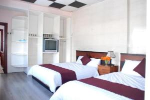 大叻New Sleep in Dalat Hostel的一间酒店客房,设有两张床和电视