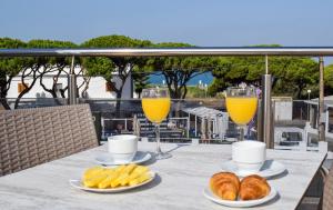 奇克拉纳－德拉弗龙特拉诺沃桑克提佩特里公寓式酒店的桌上放两杯橙汁和羊角面包,搭配饮料