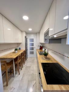 马拉加Apartamentos Prestige Malaga Suites III的厨房配有白色橱柜和木桌