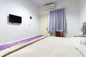 北干巴鲁Paus Guest House Pekanbaru的卧室配有一张床,墙上配有电视。