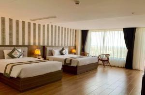 富国UM-PQ hotel Phú Quốc的酒店客房设有两张床和一张桌子。