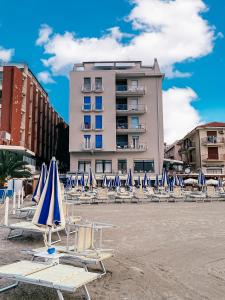 皮特拉利古Hotel Maremola的大楼前的一组沙滩椅和遮阳伞