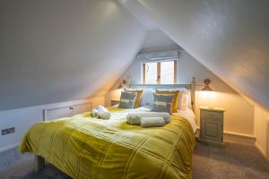 Long WittenhamPondside Barn的一间卧室配有一张大床,提供黄色毯子和枕头