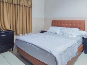 帕朗卡拉亚Hotel Halmahera Palangkaraya Mitra RedDoorz的卧室配有一张带白色床单和枕头的大床。