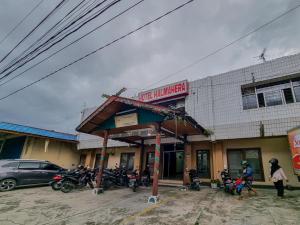 帕朗卡拉亚Hotel Halmahera Palangkaraya Mitra RedDoorz的停在大楼前的加油站,装有摩托车