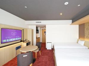 京都CHISUN PREMIUM Kyoto Kujo的一间酒店客房,设有两张床、一张桌子和一台电视机