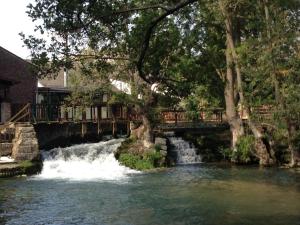 圣奥梅尔昂绍塞Logis - Hôtel & Restaurant Moulin Des Forges的一座河上的桥,有瀑布