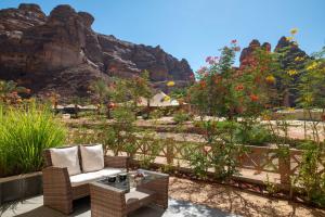 欧拉Shaden Resort的一个带椅子和桌子的庭院,并种植了一些鲜花