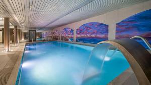 安道尔城Roc Blanc Hotel & Spa的墙上挂有壁画的大型游泳池