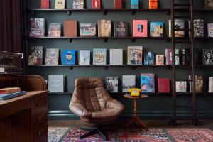 阿姆斯特丹阿姆斯特丹普利策酒店的一间房间,配有椅子和书架及书籍
