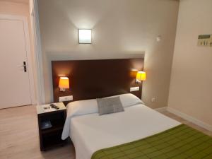 哈罗 阿洛佩酒店的卧室配有一张白色大床和两盏灯。