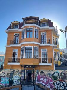 瓦尔帕莱索Casa Vander Hotel Boutique的旁边是一座涂有涂鸦的黄色建筑