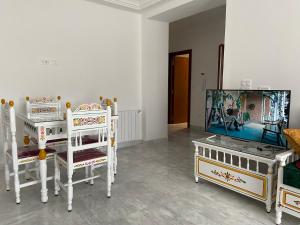 拉马萨Marsa Authentic Luxury Appart 1的客厅配有3把白色椅子和电视