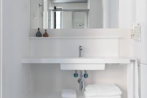 马德里Apartamentos Las Torres的浴室设有白色水槽和镜子