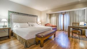 安道尔城Roc Blanc Hotel & Spa的一间卧室配有一张大床、一张书桌和一张四柱床。