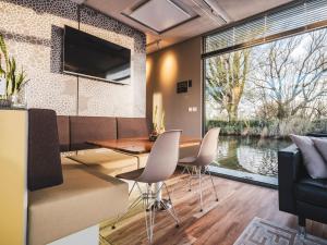 WerkendamAquaHome - NP de Biesbosch - Bijzonder overnachten op een houseboat!的一间带桌椅和大窗户的用餐室
