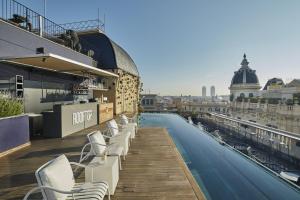 巴塞罗那巴塞罗那奥拉酒店的一座屋顶游泳池,在大楼内摆放着白色椅子