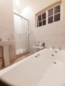 德班Rehoboth Guesthouse的白色的浴室设有浴缸和水槽。